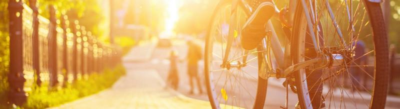 A person riding a bike on a street in a sunshine.